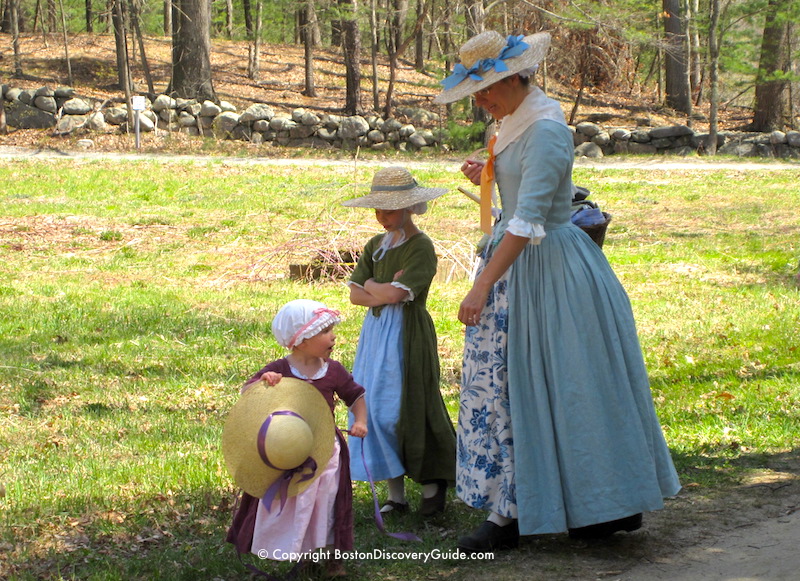 Reenactor portraying a Colonial woman with two young daughters during Patriots Day celebration